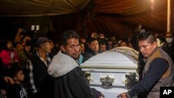 Kerabat membawa peti mati bersama jenazah Jair Valencia, Misael Olivares, dan Yovani Valencia di rumah keluarga mereka di San Marcos Atexquilapan, negara bagian Veracruz, Meksiko, Rabu, 13 Juli 2022. (AP/Felix Marquez)