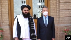 FILE - In this photo released by the Xinhua News Agency, Chinese Foreign Minister Wang Yi, right, poses for photos with Amir Khan Muttaqi, acting foreign minister of the Afghan Taliban's caretaker government, in Kabul, Afghanistan, March 24, 2022. (Xinhua/AP)