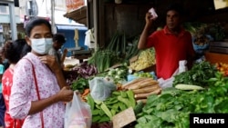 FILE - A vendor sells vegetables to a customer amid the rampant food inflation, amid Sri Lanka's economic crisis, in Colombo, Sri Lanka, July 29 , 2022.