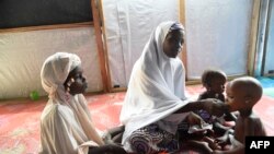 Une mère nourrit un enfant souffrant de malnutrition dans une clinique mise en place par les autorités sanitaires avec Médecins Sans Frontières ou Médecins Sans Frontières (MSF) dans l'État de Katsina, au nord-ouest du Nigeria, le 20 juillet 2022.