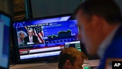 FILE - As traders work and watch, a news conference held by Federal Reserve Chair Jerome Powell is displayed at the New York Stock Exchange in New York, July 27, 2022.