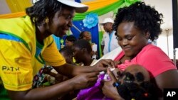 FILE - A health worker vaccinates a child against malaria in Homabay County, western Kenya, Sept.13, 2019. Malaria hospitalizations and deaths fell the vaccine's pilot program countries of Kenya, Ghana and Malawi and a mass rollout of the vaccine is underway.