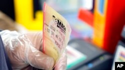 Andres Fernandez sells Mega Millions lottery tickets at a Chevron station in Oakland Park, Fla., on July 29, 2022. 