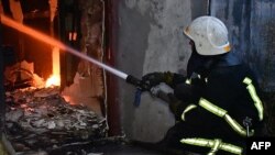 This handout picture taken and released by Ukraine Emergency Service on July 25, 2022, shows a firefighter facing a fire in front of a burning residential building after a shelling in Mykolaiv region. (Photo by Ukraine Emergency Service / AFP)