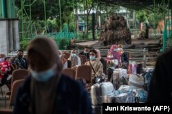 Buruh migran yang kembali dari Malaysia dan Singapura menunggu pemeriksaan COVID-19 di Surabaya pada 28 April 2021, sebelum dikarantina. (Foto: AFP/Juni Kriswanto)