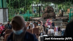 Buruh migran yang kembali dari Malaysia dan Singapura menunggu pemeriksaan COVID-19 di Surabaya pada 28 April 2021, sebelum dikarantina. (Foto: AFP/Juni Kriswanto)