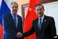 Russian Foreign Minister Sergey Lavrov, left, and Chinese Foreign Minister Wang Yi pose for a photo prior to their talks on the sideline of the 12th East Asia Summit foreign ministers' meeting in Phnom Penh, Cambodia, Friday, Aug. 5, 2022. (Russian Foreign Ministry Press Service via AP)