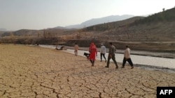 This handout photo made available by the Iranian Red Crescent Society (RCS) on July 23, 2022, shows rescue worker searching near a river bank after flooding in southern Iran.