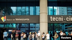 La gente se para fuera de un banco para retirar efectivo y obtener nuevos billetes de mayor denominación, en Caracas, Venezuela, 16 de marzo de 2021.