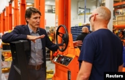 Canada's Prime Minister Justin Trudeau speaks with a worker during his tour at the factory of Motrec International, a company that builds customizable electric industrial vehicles, in Sherbrooke, Quebec, Canada, July 12, 2022.