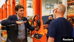 Perdana Menteri Kanada Justin Trudeau berbicara dengan salah satu pekerja di Pabrik Motrec International dalam kunjungannya ke pabrik pembuatan kendaraan listrik untuk industri itu di Sherbrooke, Quebec, Kanada, pada 12 Juli 2022. (Foto: Reuters/Evan Buhler)