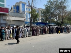 FILE - Afghans line up outside a bank to take out their money after Taliban takeover in Kabul, Afghanistan, Sept. 1, 2021.