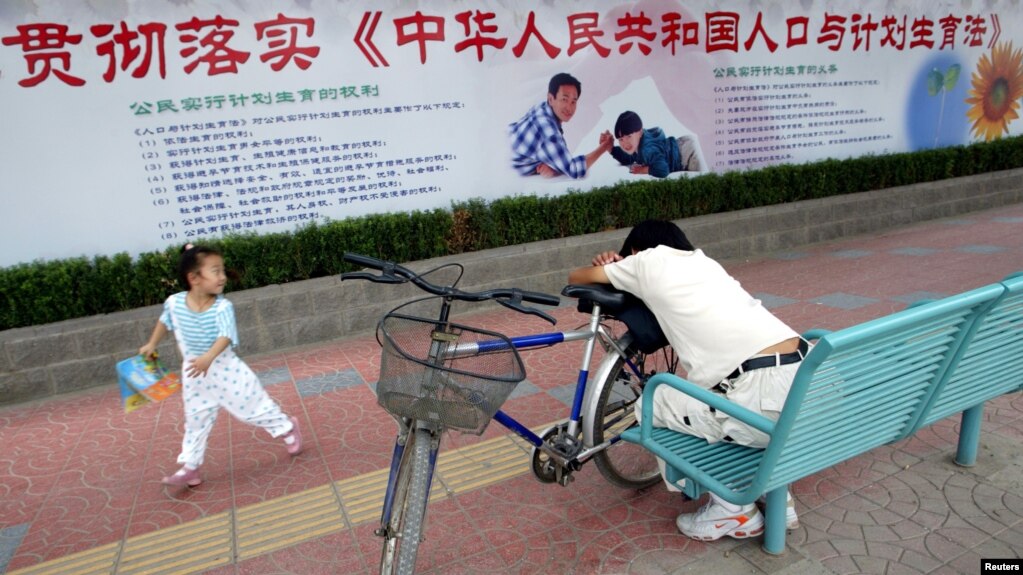 资料照：北京街道上一名小女孩在宣传中国人口与计划生育法的宣传栏下玩耍。 (photo:VOA)