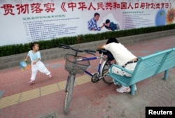 资料照：北京街道上一名小女孩在宣传中国人口与计划生育法的宣传栏下玩耍。