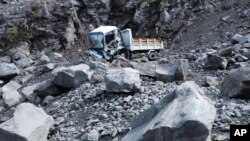 Un camión dañado, junto a las rocas que cayeron sobre una carretera durante un sismo en Bauko, en la provincia de La Montaña, Filipinas, el 27 de julio de 2022. (AP Foto/Harley Palangchao)