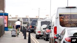 A man cycles with a suitcase past traffic jams as many families embark on getaways at the start of summer holidays for many schools in England and Wales, in Dover, England, July 22, 2022.