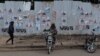 Un chauffeur de moto-taxi attend des clients devant un mur recouvert d'affiches de campagne à Kisumu, dans l'ouest du Kenya, le 16 juillet 2022.