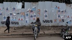 Un chauffeur de moto-taxi attend des clients devant un mur recouvert d'affiches de campagne à Kisumu, dans l'ouest du Kenya, le 16 juillet 2022.