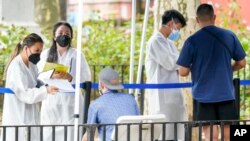 Trabajadores de salud con ayudantes del Departamento de Salud e Higiene de la ciudad de Nueva York laboran en un sitio de vacunas contra la viruela símica, el martes 26 de julio de 2022, en Nueva York. (AP Foto/Mary Altaffer)