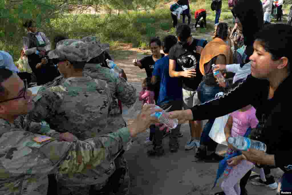 Agentes de la Guardia Nacional de Estados Unidos ofrecen agua a los migrantes que cruzaron el río desde México en busca de asilo.