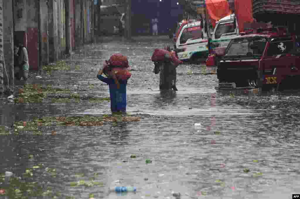 Laborers carry sacks of onions in a flooded market after a heavy rain shower in Lahore, Pakistan.