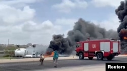 Smoke billows from a plane that flipped over after crash-landing, in Mogadishu, Somalia, July 18, 2022, in this screen grab from social media video obtained by Reuters.