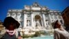 Varias personas se sientan cerca de la fuente de Trevi cuando una ola de calor golpea Europa, en Roma, Italia, el 19 de julio de 2022. REUTERS/Guglielmo Mangiapane