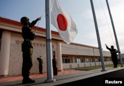 日本冲绳县宫古岛一个军营里的自卫队成员在晚间举行降旗仪式。（2022年4月20日）