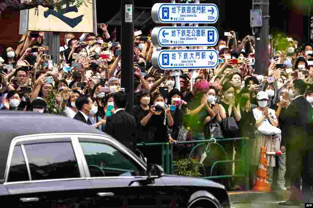 People watch the hearse transporting the body of late former Japanese prime minister Shinzo Abe as it leaves Zojoji Temple in Tokyo.