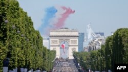 French elite acrobatic flying team "Patrouille de France" (PAF) release smoke in the colours of the French flag as they perform a fly-over during the Bastille Day military parade on the Champs-Elysees avenue in Paris, July 14, 2022. 