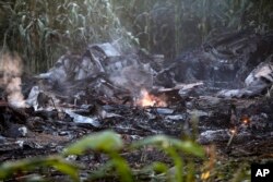 A flame is seen amid debris of an Antonov cargo plane in Palaiochori village in northern Greece, July 17, 2022, after it reportedly crashed Saturday near the city of Kavala.