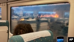 Pasajeros de un tren toman fotos de un incendio forestal en Zamora, España, el lunes 18 de julio de 2022. (Foto AP/Francisco Seoane Pérez)
