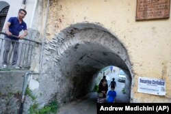 Rabi Barbara Aiello, tengah bawah, bergandengan tangan dengan Noah Blum, 10, saat tur ke kawasan Yahudi di Lamezia Terme, Italia selatan, Kamis, 7 Juli 2022. (Foto: AP/Andrew Medichini )