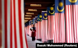 Seorang mahasiswa Universitas Nasional Malaysia berjalan melewati jajaran bendera nasional Malaysia di luar Kuala Lumpur 22 Agustus 2007. (Foto: Reuters/Bazuki Muhammad)