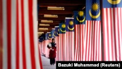 Seorang mahasiswa Universitas Nasional Malaysia berjalan melewati jajaran bendera nasional Malaysia di luar Kuala Lumpur 22 Agustus 2007. (Foto: Reuters/Bazuki Muhammad)