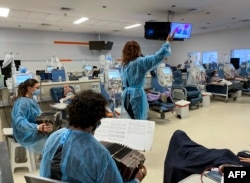 Pemain Bandoneon Abril Farolini, Ramiro Hernández, dan penyanyi Paola Larrama, tampil di ruang dialisis untuk pasien ginjal, Diaverum Center, di Montevideo, 17 Juni 2022. (Lucia LACURCIA / AFP)