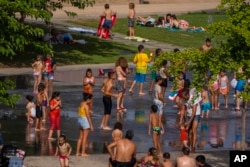 FILE - Children cool off in a fountain in a park by the river in Madrid, Spain, June 17, 2022.