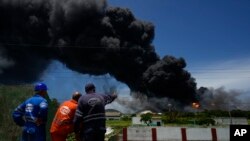 Los trabajadores del Sindicato Petrolero de Cuba, conocido por el acrónimo CUPET, observan una enorme columna de humo que se eleva desde la Base de Supertanqueros de Matanzas. (Foto AP/Ramón Espinosa)