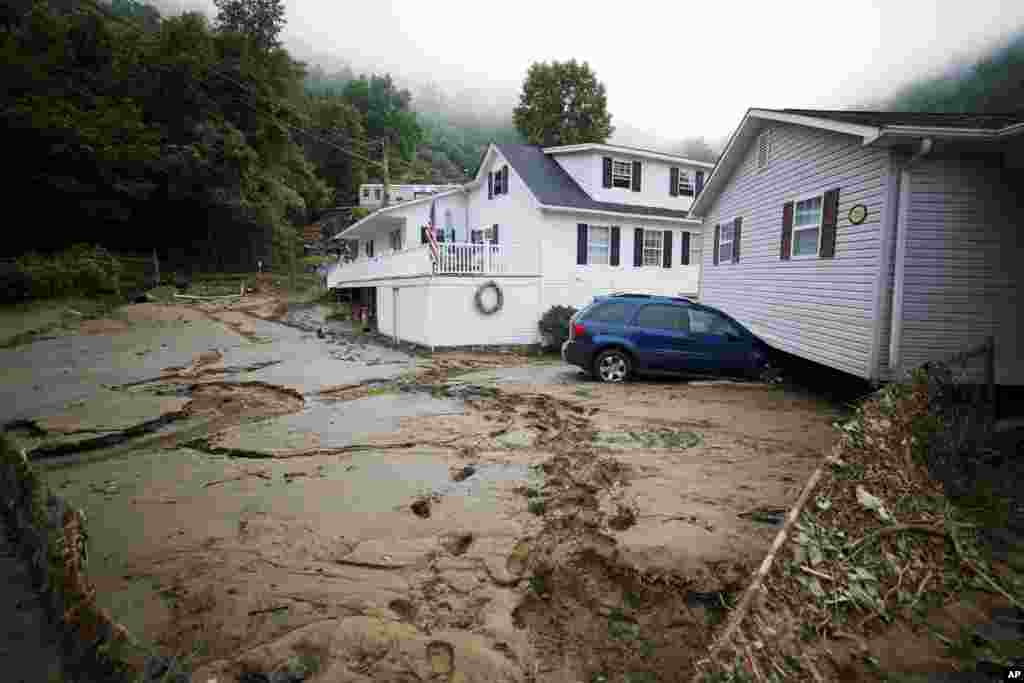 A house that was moved off of its foundation following a flash flood rests on top of a vehicle in Whitewood, Virginia.