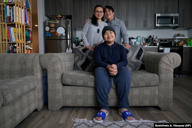 Eleonor Obedoza, her husband Arman, and son Angelo, 12, sit inside their new three-bedroom apartment in Daly City, California, July 8, 2022. (AP Photo/Godofredo A. Vásquez)