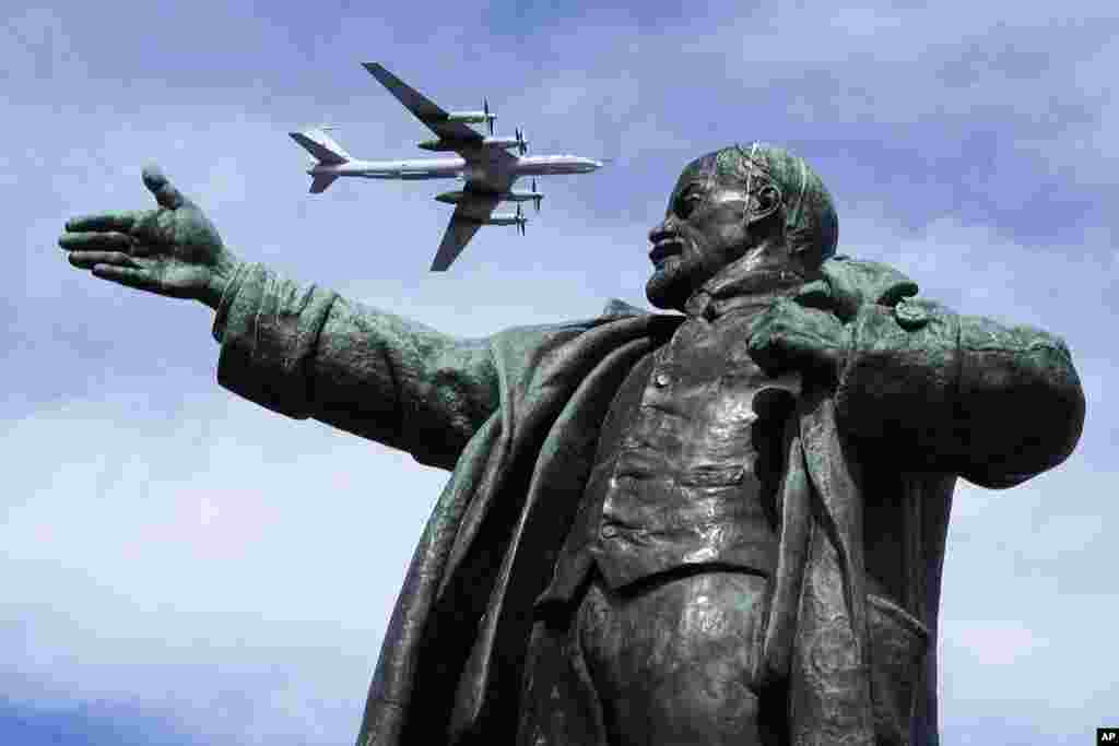 A Tupolev Tu-142MK, a Soviet and Russian maritime reconnaissance and anti-submarine warfare aircraft, flies above a statue of Soviet Union founder Vladimir Lenin during a rehearsal of the Naval parade in St.Petersburg, Russia.