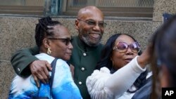 FILE - Muhammad Aziz, center, stands outside the courthouse with members of his family after his conviction in the killing of Malcolm X was vacated, Thursday, Nov. 18, 2021, in New York.