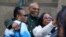FILE - Muhammad Aziz, center, stands outside the courthouse with members of his family after his conviction in the killing of Malcolm X was vacated, Thursday, Nov. 18, 2021, in New York.
