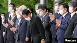 El primer ministro de Japón, Fumio Kishida, funcionarios y empleados oran en dirección de un coche fúnebre que lleva el cuerpo del fallecido ex primer ministro japonés Shinzo Abe, en Tokio, Japón, el 12 de julio de 2022.
