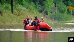 2022年7月28日，肯塔基州温彻斯特消防队成员推着充气艇走过杰克逊的一条被水淹没道路以接运被洪水围困的人。