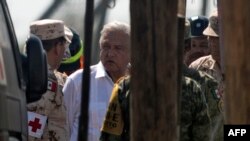 Presiden Meksiko Andres Manuel Lopez Obrador (tengah) berbicara dengan regu penyelamat di tambang batu bara yang kebanjiran, tempat 10 penambang terperangkap sejak Rabu, di komunitas Agujita, Kota Sabinas, Coahuila, Meksiko, 7 Agustus 2022. (Julio Cesar AGUILAR / AFP)