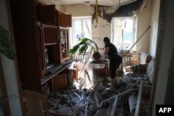 A woman clean her house from debris after a Russian missile strike in the town of Konstantinovka, Donetsk region on July 16, 2022 amid Russian military invasion of Ukraine.