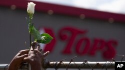 Cariol Horne places a rose on the fence outside the Tops Friendly Market on July 14, 2022, in Buffalo, New York. The supermarket where 10 Black people were killed by a white gunman is set to reopen its doors, two months after the racist attack. 