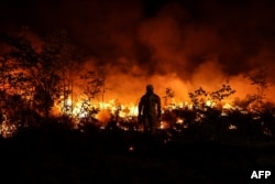 Petugas pemadam membakar lahan untuk mencegah api meluas akibat perubahan angin saat memadamkan kebakaran hutan di Louchats, Gironde, Prancis, 17 Juli 2022. (Foto: AFP)