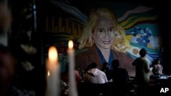 Varias velas arden cerca de un mural con la imagen de la fallecida ex primera dama de Argentina, María Eva Duarte de Perón, más conocida como "Evita", en el restaurante "El Santa Evita", en Buenos Aires, Argentina, el 24 de junio. Julio de 2022.